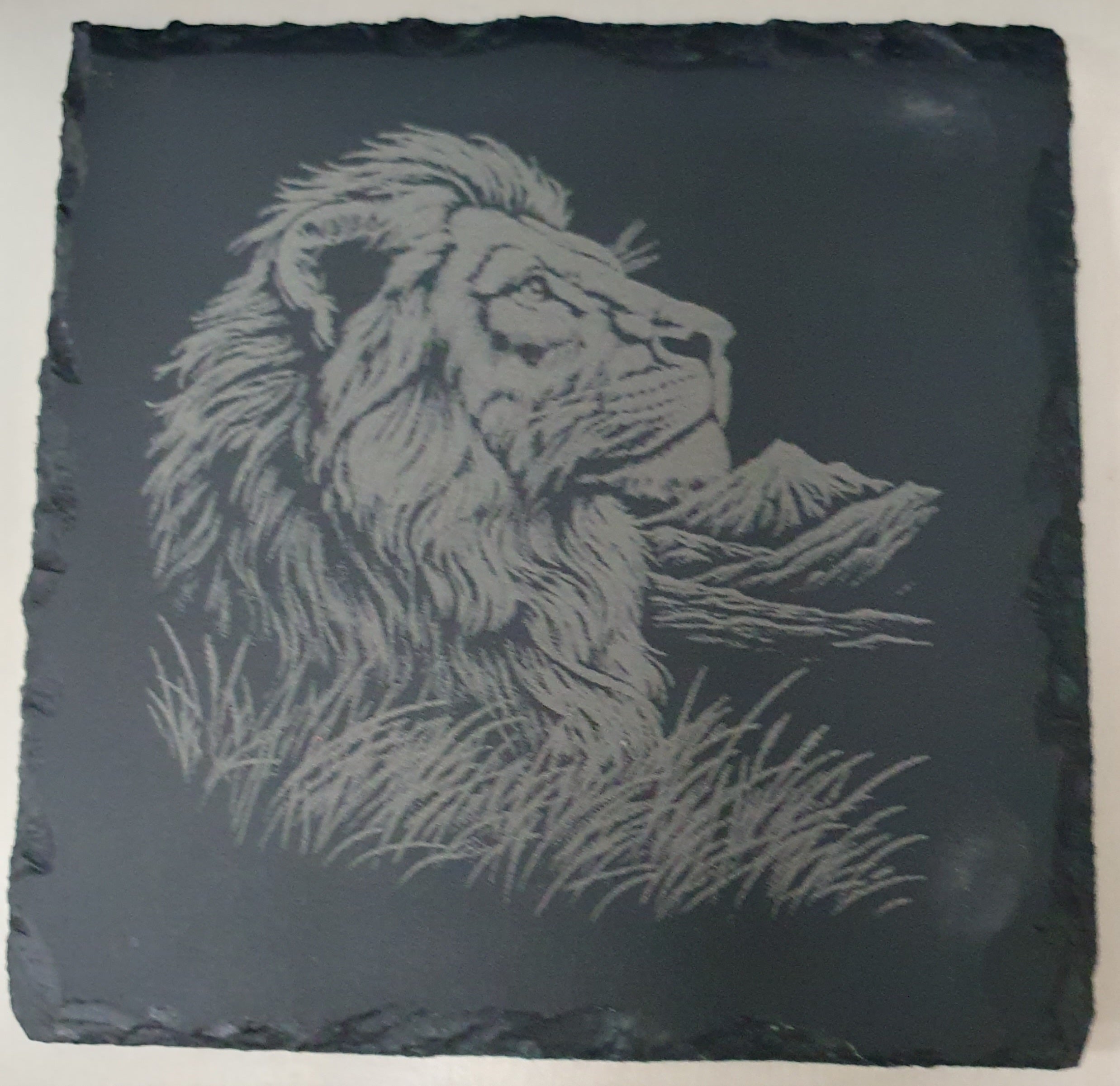 Slate tile with engraved lion design.