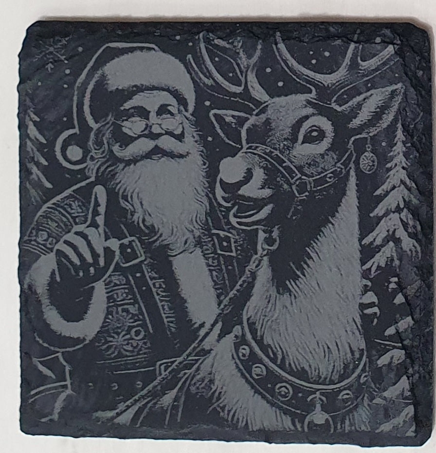 Decorative stone with engraved illustration of Santa Claus and a reindeer against a snowy background.