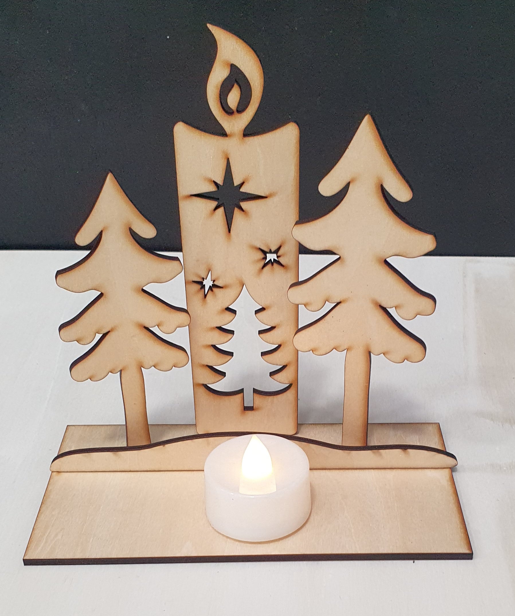 Wooden candle holder with trees and a star design on a white background