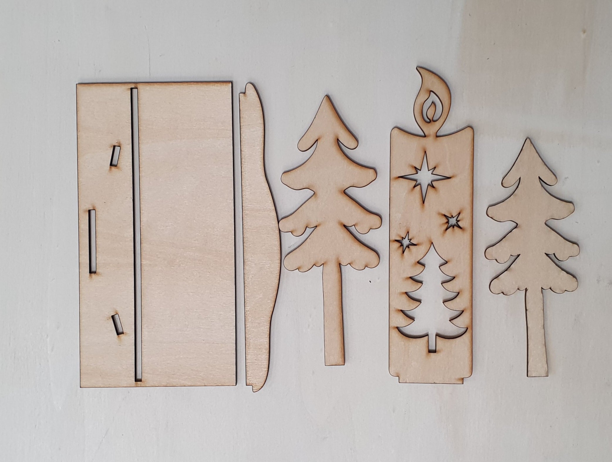 Wooden cutouts of a door, sword, trees, and candle on a white background