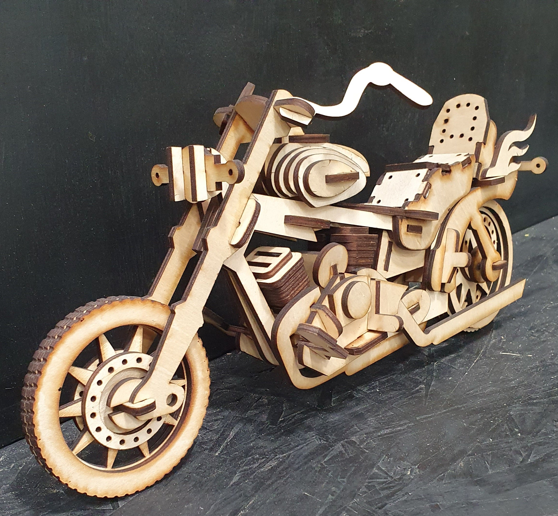 Flat-pack MDF motorcycle model kit showing layered laser-cut parts
