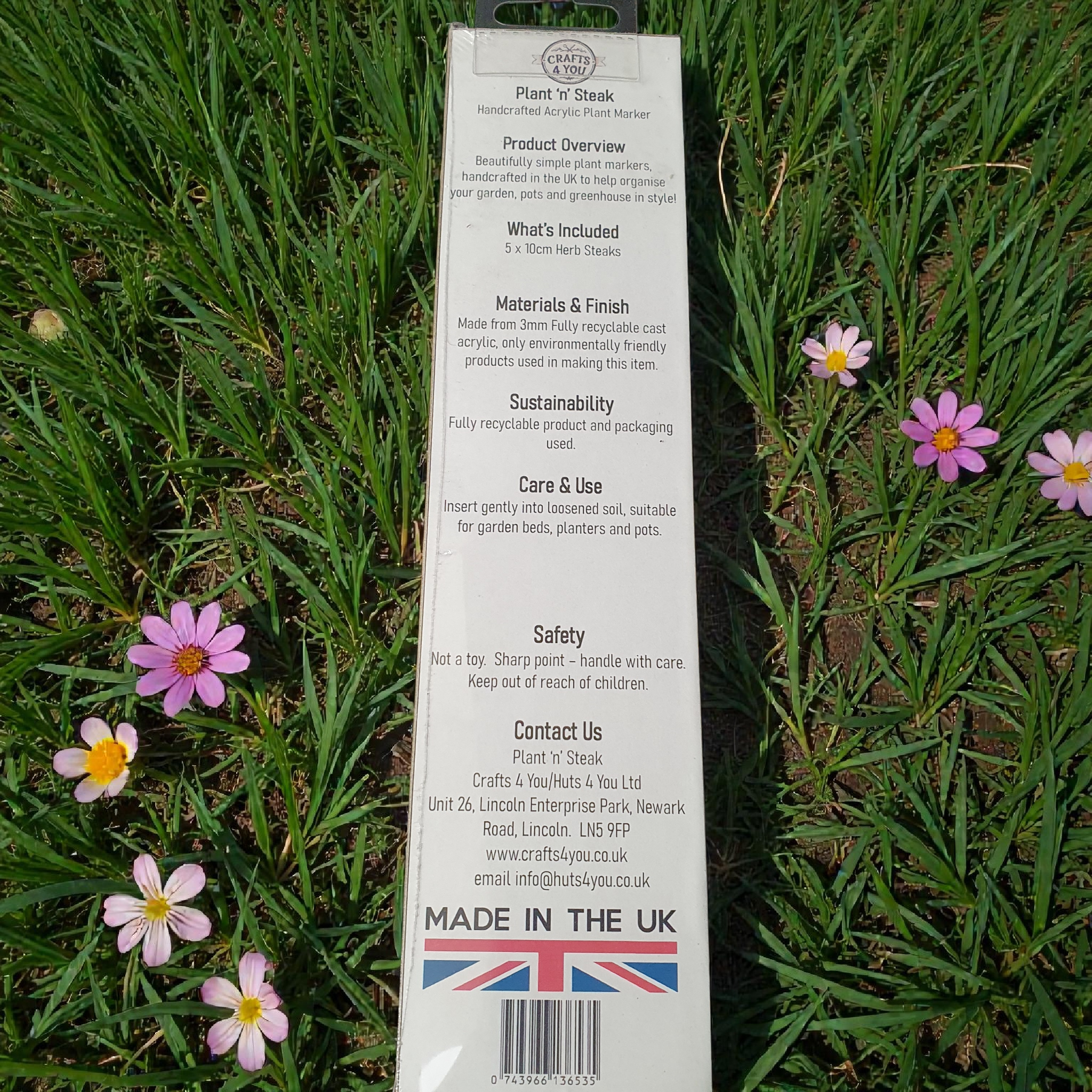 Back of herb plant marker packaging displayed outdoors on grass, showing product details, sustainability information and Made in the UK branding.