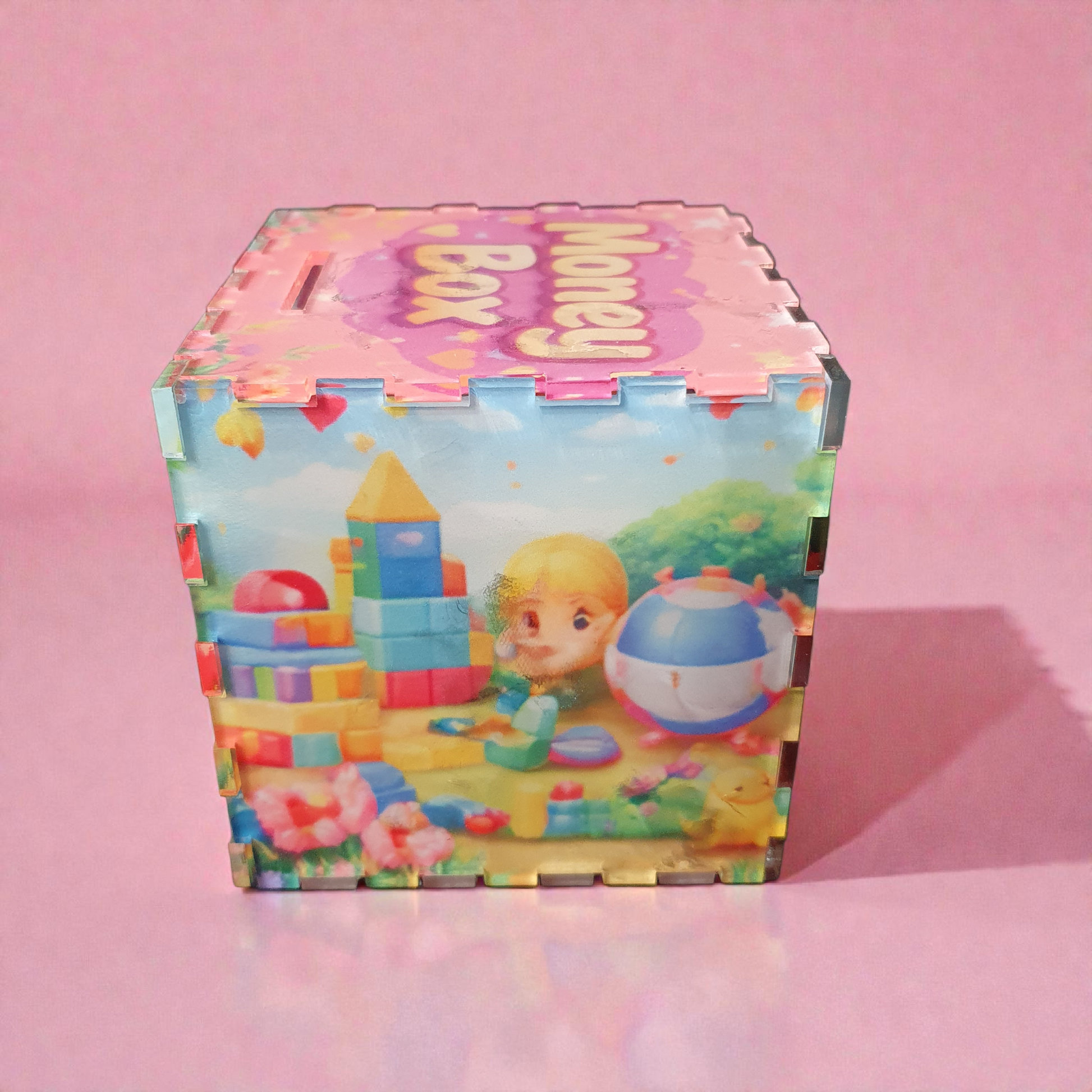 Side view of acrylic kids money box featuring child playing with colourful building blocks and ball.