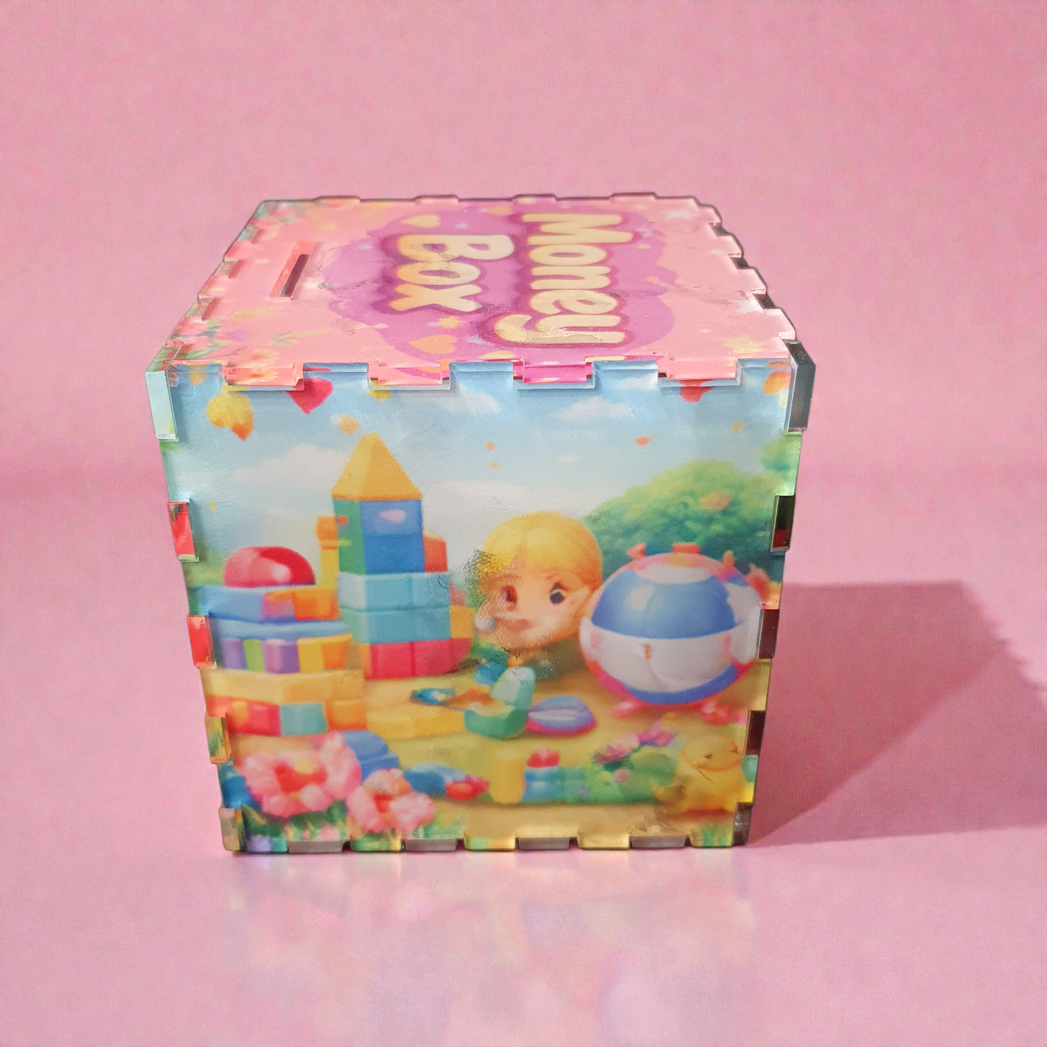Side view of acrylic kids money box featuring child playing with colourful building blocks and ball.