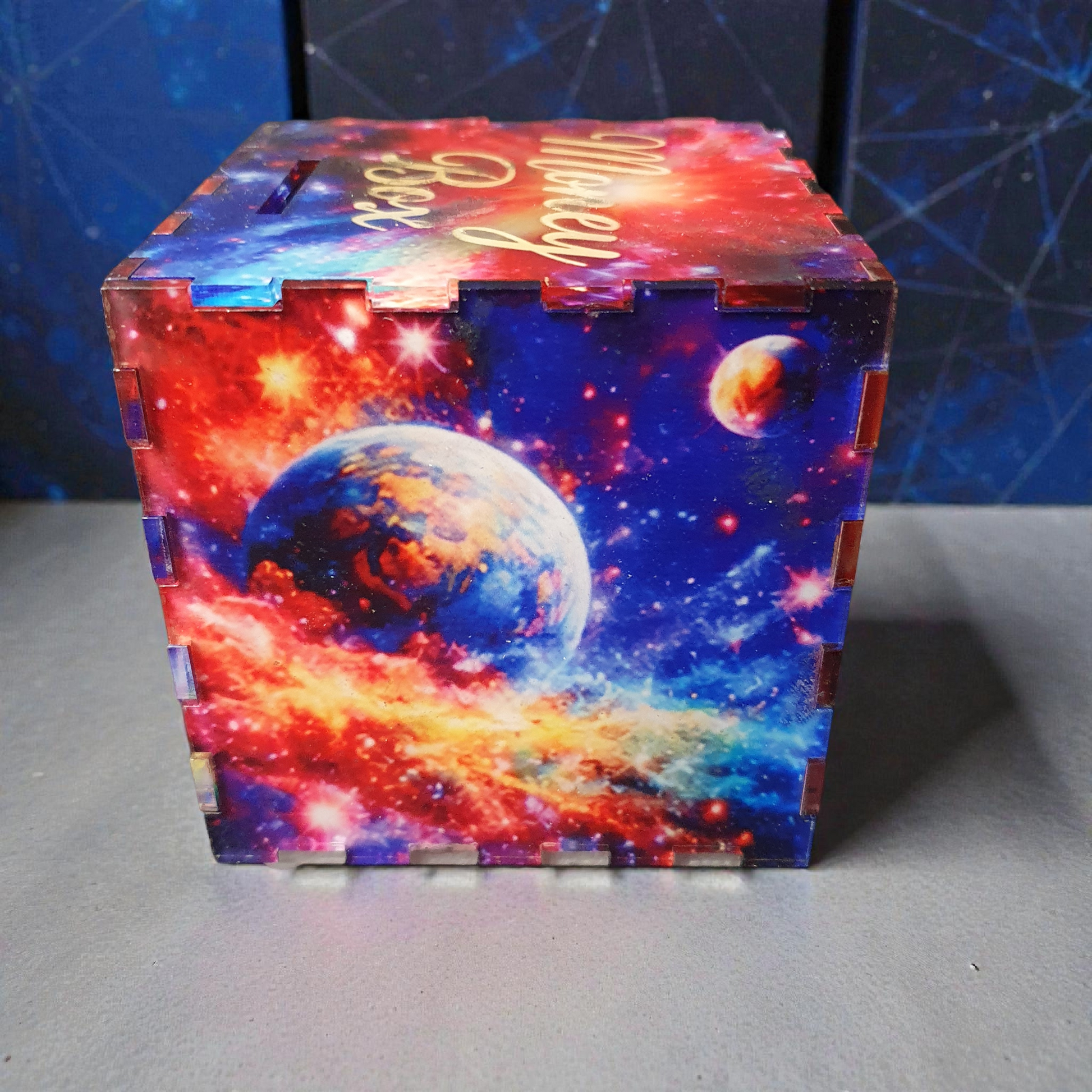 Rear view of galaxy money box displaying Earth-style planet and swirling star field design in vivid red, orange and blue tones.