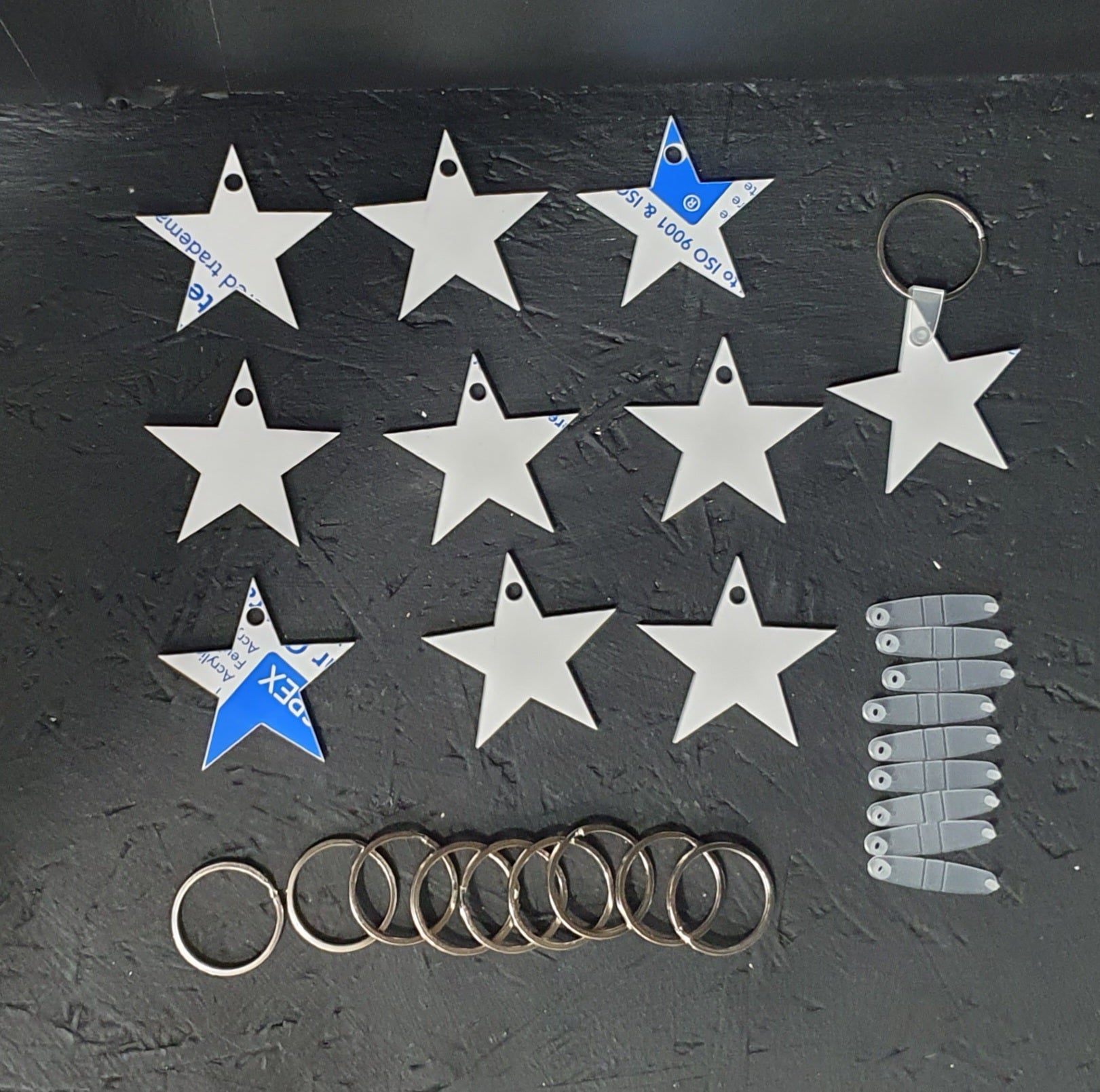 Star shaped white cast acrylic keyring blank approximately 50mm wide with smooth laser cut edges and clear connector tab with metal split ring.