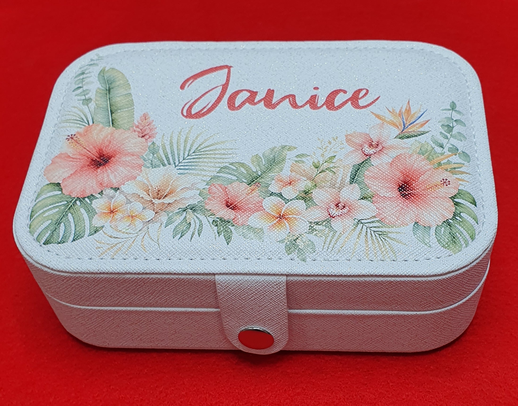 Personalised white travel jewellery box with the name Janice printed on the lid, decorated with tropical hibiscus flowers and botanical leaves, ideal for storing rings, earrings and necklaces.