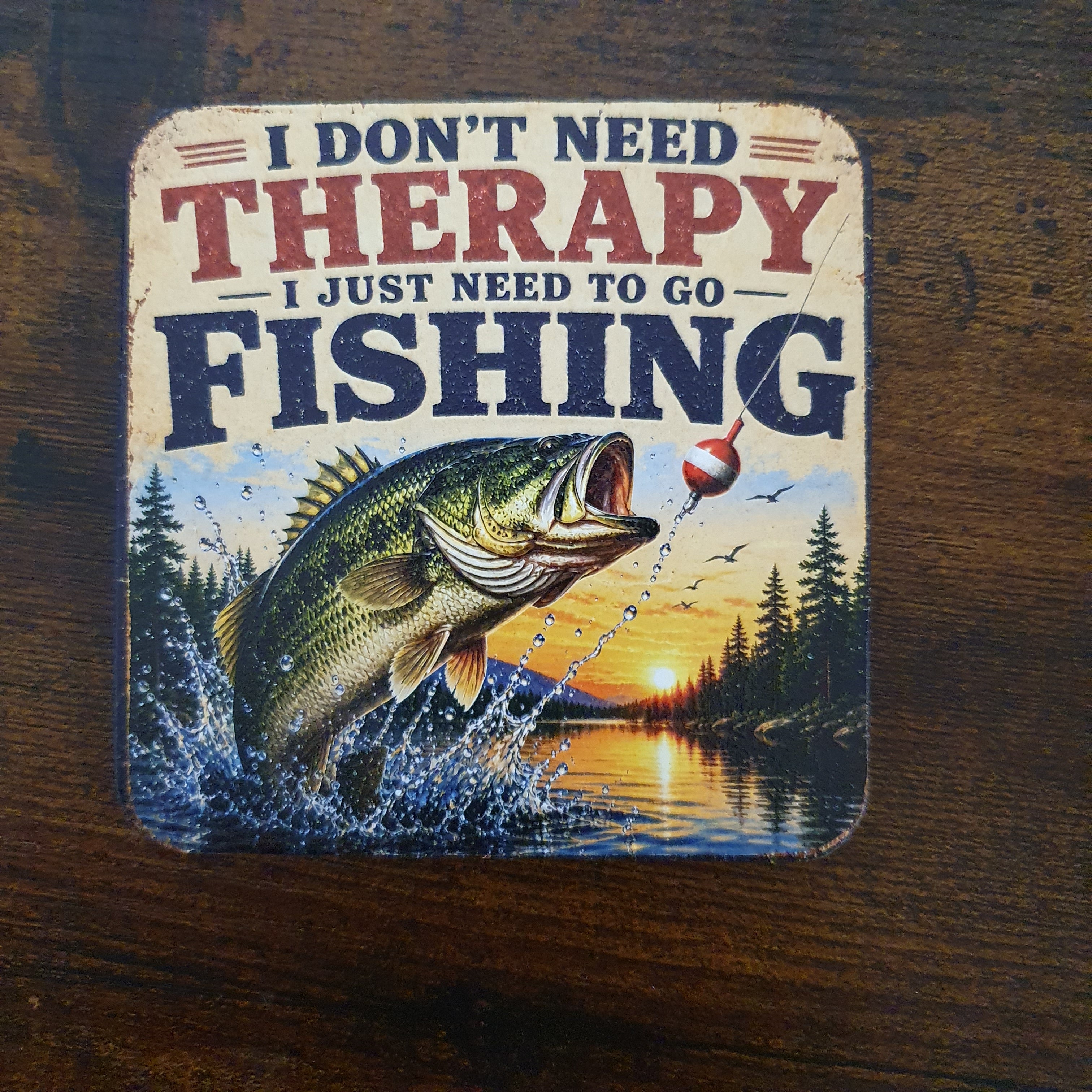 Wooden fishing coaster featuring the humorous quote "I Don't Need Therapy I Just Need To Go Fishing" with a leaping bass and sunset lake scene, finished with textured UV printing.