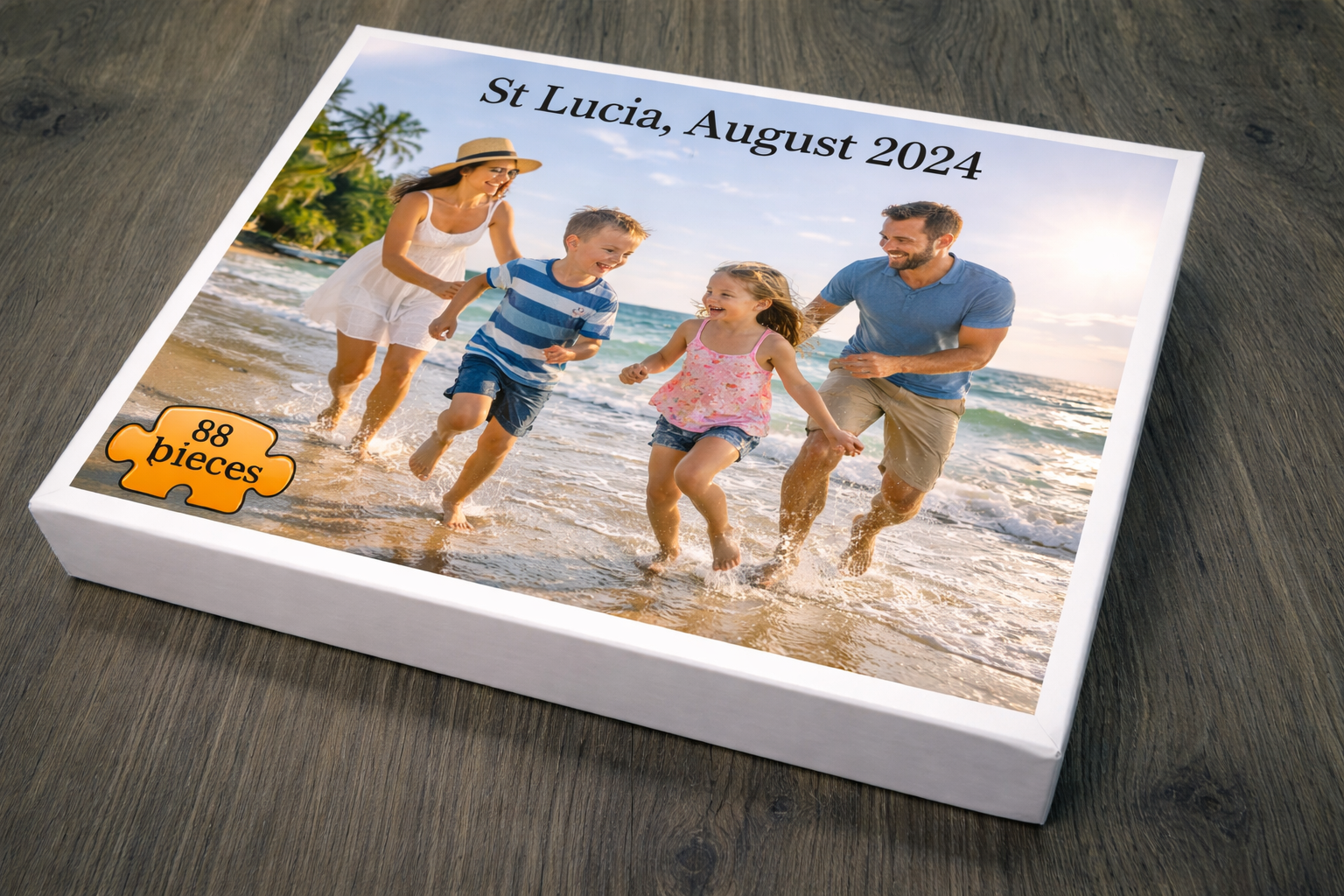 A custom square jigsaw puzzle box displayed on a dark wood surface. The box features a printed photo of a family of four running and playing on a beach in St.