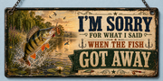 A rectangular metal sign featuring a yellow and black striped fish jumping out of water with a fishing lure in its mouth. The text reads I'M SORRY FOR WHAT I SAID WHEN THE FISH GOT AWAY. The background depicts a lake at sunset.