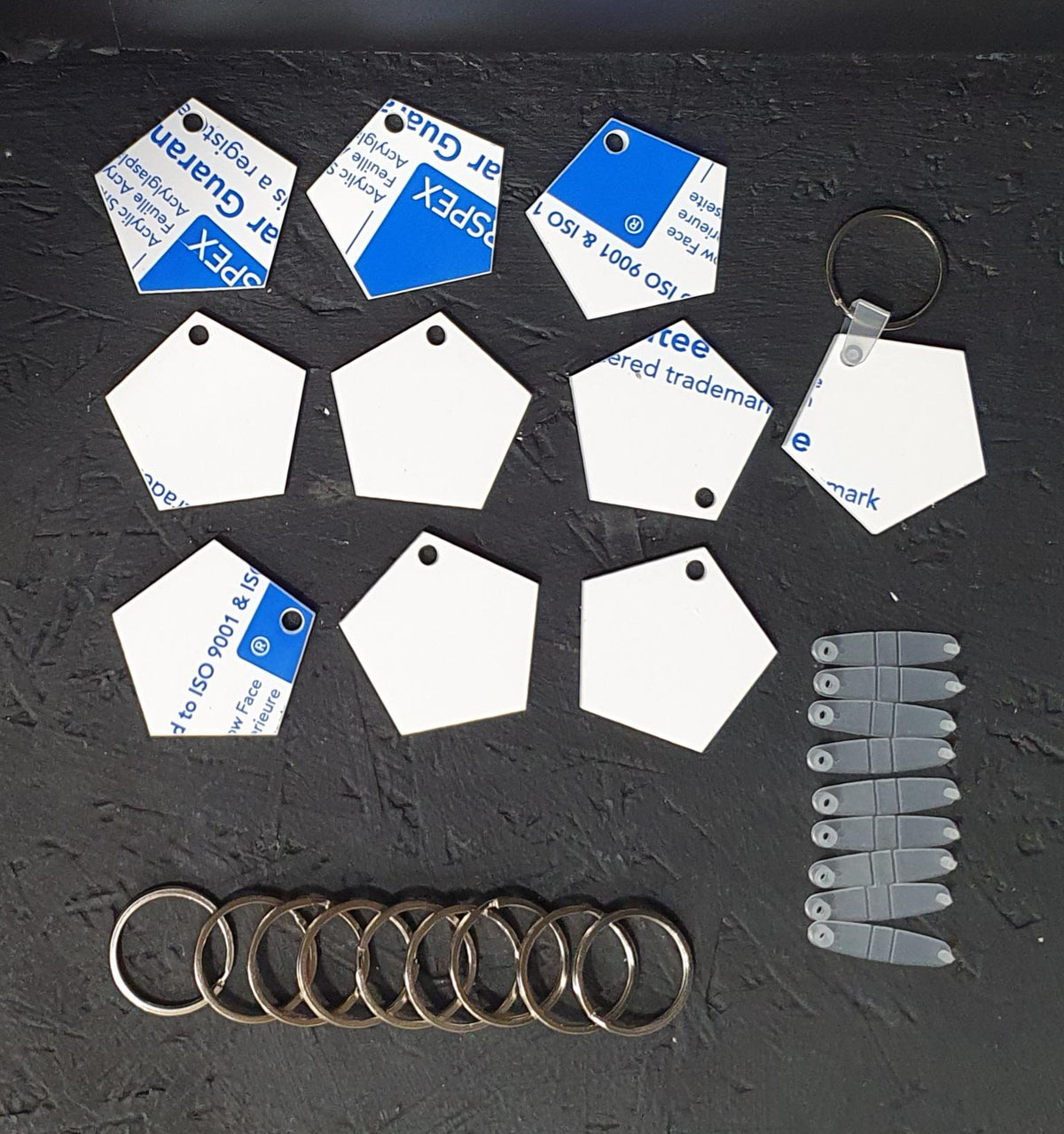 Pentagon shaped white cast acrylic keyring blank with smooth finish and sturdy keyring attachment for personalised craft projects.
