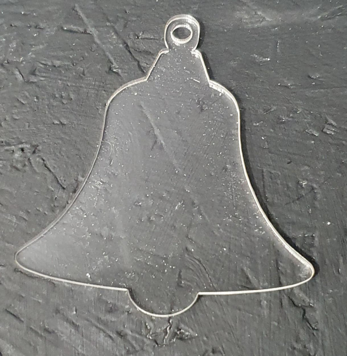 Close up of clear cast acrylic bell blank with protective film applied, highlighting transparency, clean cut finish and 5mm hanging hole detail.