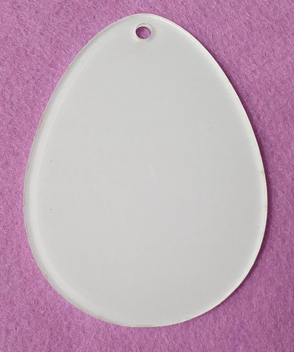 White cast acrylic Easter egg blank close up showing smooth surface, clean laser cut edges and top hanging hole suitable for vinyl, sublimation and UV printing.