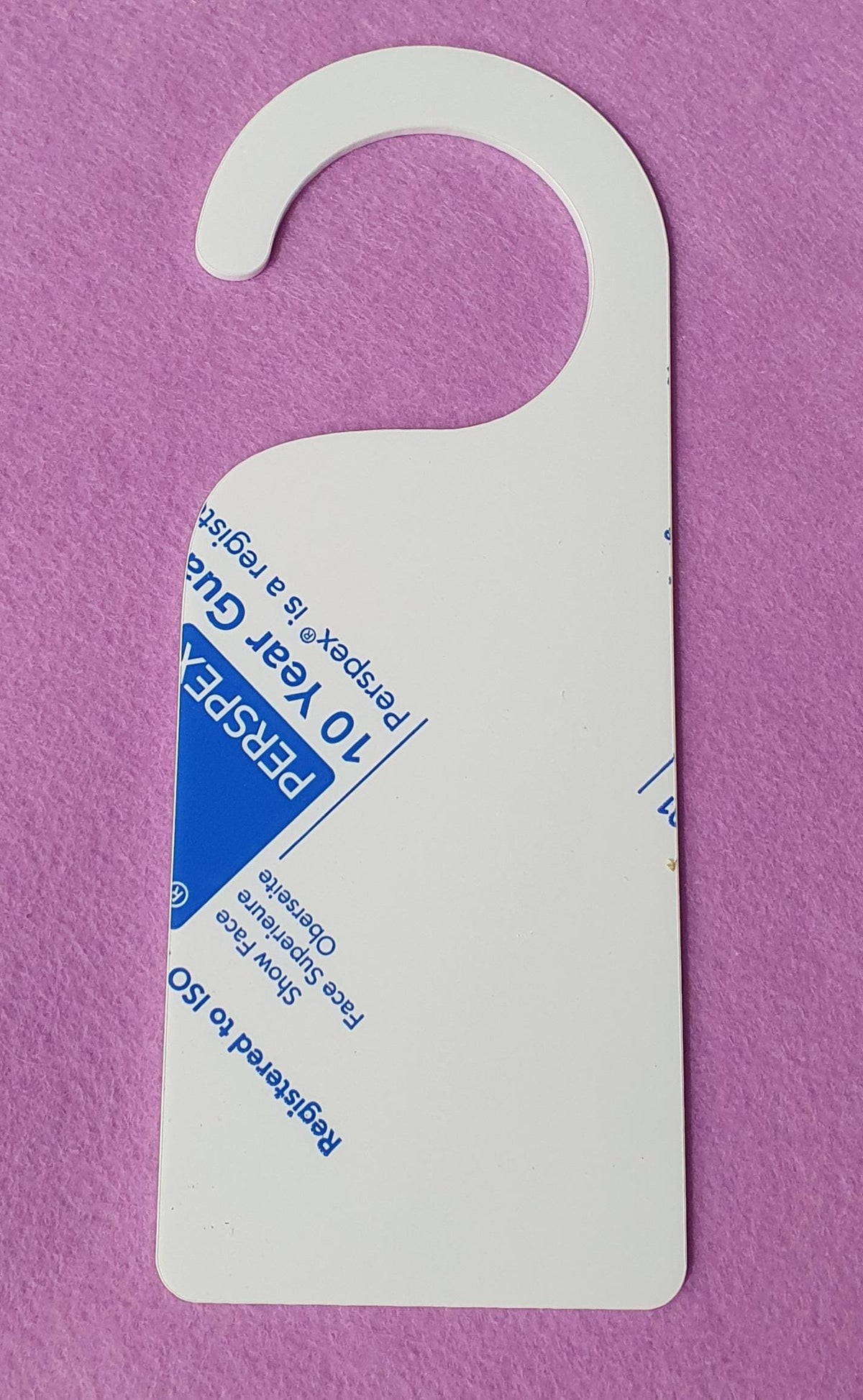 White 3mm acrylic door hanger blank measuring 23cm x 9cm shown flat on pink background with protective film partially visible, precision laser cut with smooth rounded hook.