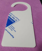 Close up angled view of white acrylic door hanger blank highlighting 3mm thickness, smooth surface finish and curved hook cut-out for standard door handles.