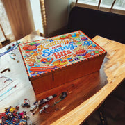 Wooden knitting and sewing storage box with colourful acrylic “Knitting and Sewing Bits” lid displayed closed on red background