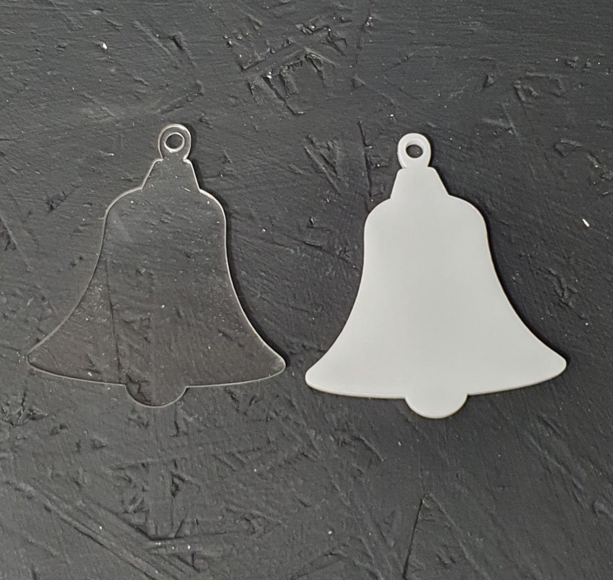 Clear and white acrylic bell blanks displayed side by side showing smooth laser cut edges and optional hanging hole at the top, suitable for sublimation, vinyl and UV printing.