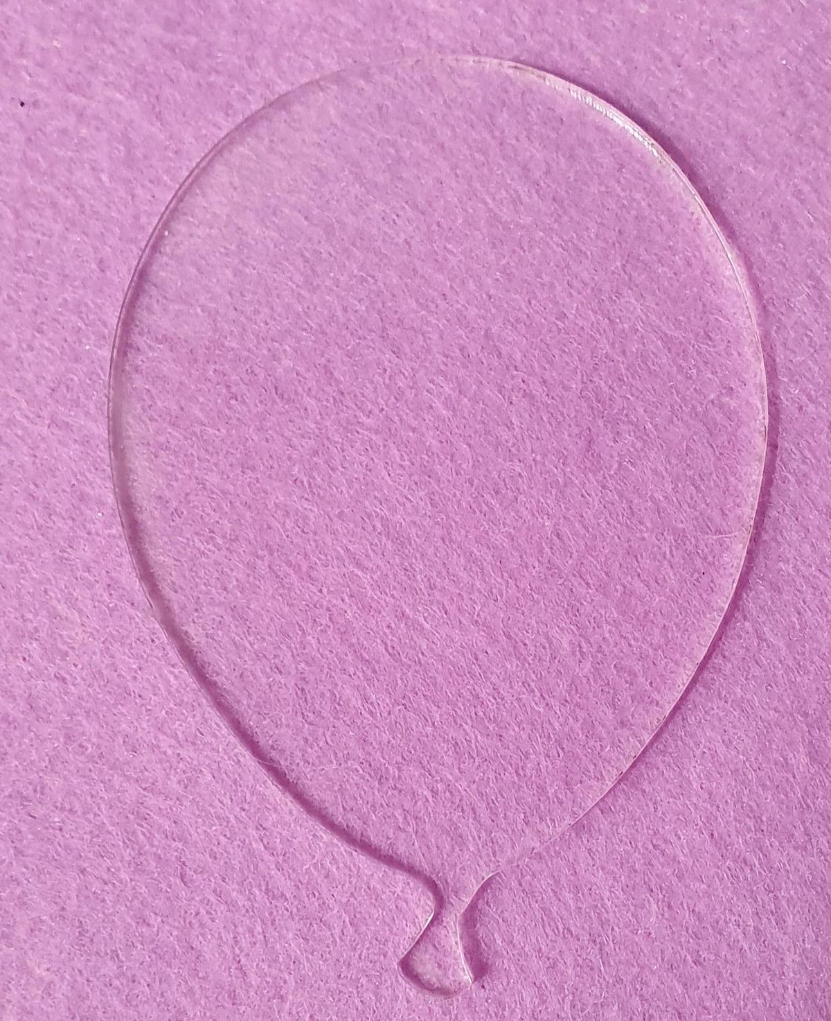 Clear acrylic balloon shape blank displayed on pink background highlighting transparent finish and clean outline for personalised decorations.