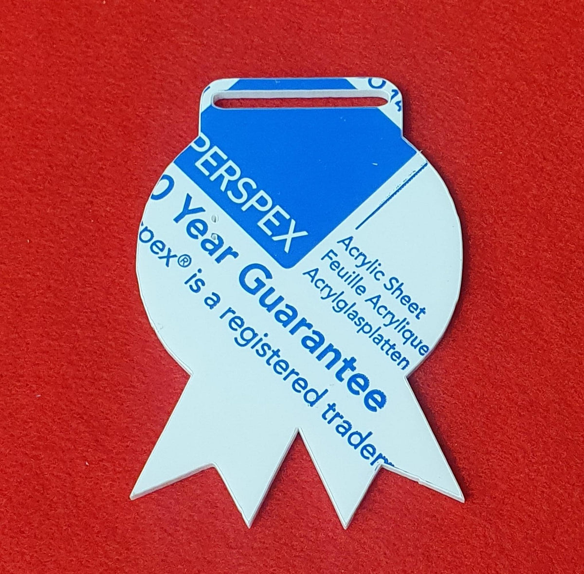 Acrylic rosette medal blank 10cm x 7cm with ribbon slot, shown in white cast acrylic with protective film.
