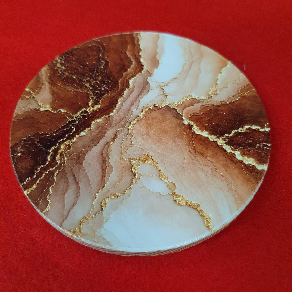 Terracotta marble effect coaster with textured gold veining held in hand, round 10cm cork backed drink coaster warm home decor
