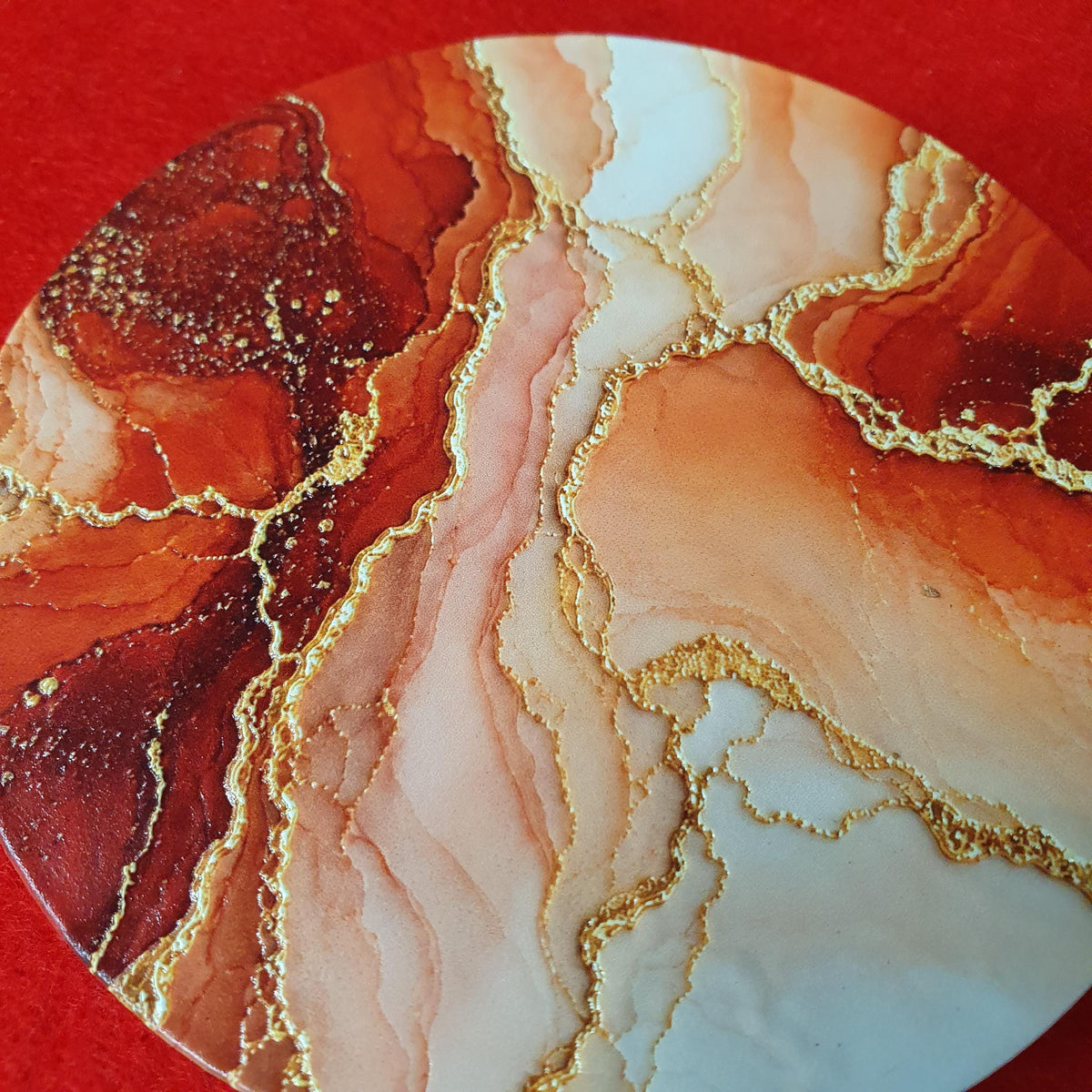 Terracotta marble effect coaster with textured gold veining held in hand, round 10cm cork backed drink coaster warm home decor