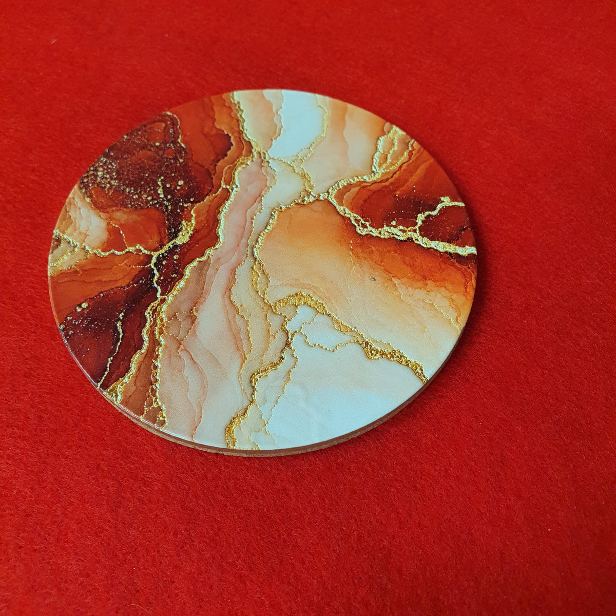 Terracotta marble effect coaster with textured gold veining held in hand, round 10cm cork backed drink coaster warm home decor
