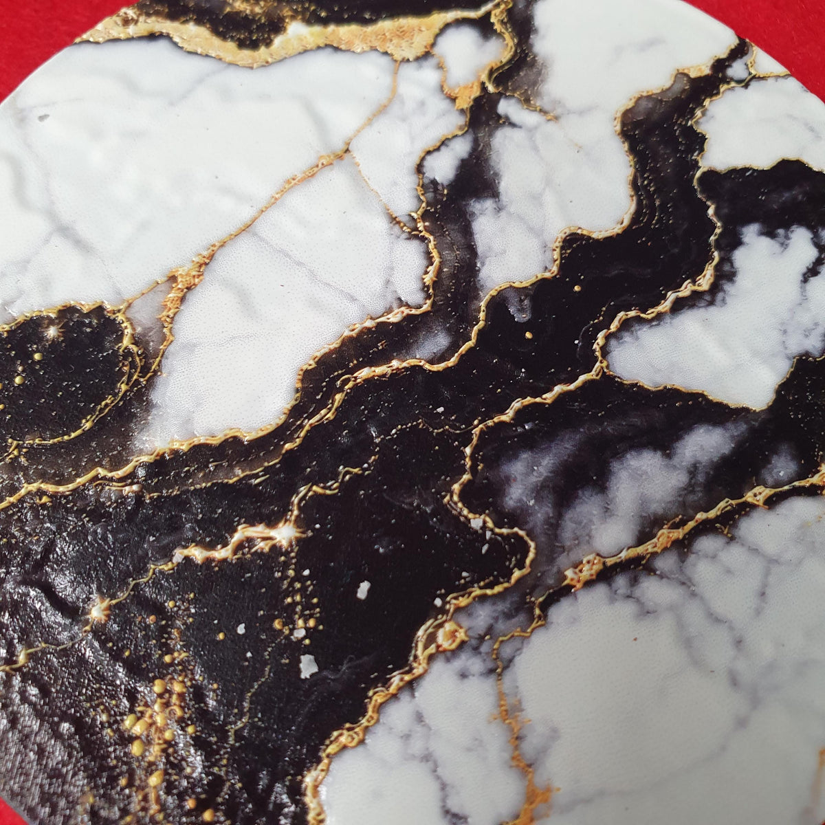 Luxury black marble effect coaster with white marble sections and elegant gold veining.