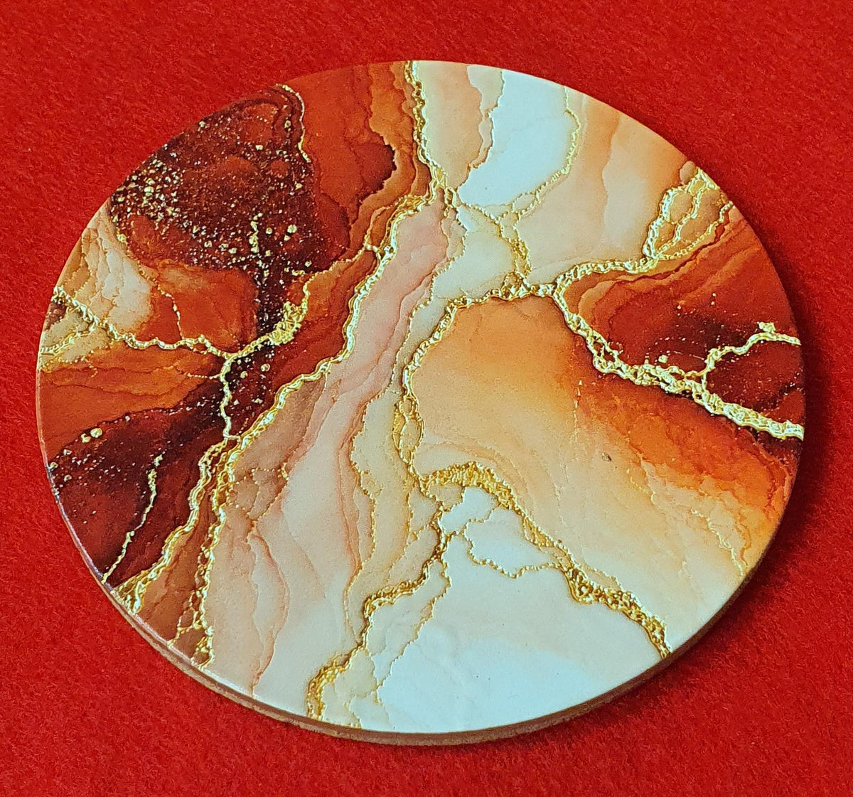 Terracotta marble effect coaster with textured gold veining held in hand, round 10cm cork backed drink coaster warm home decor