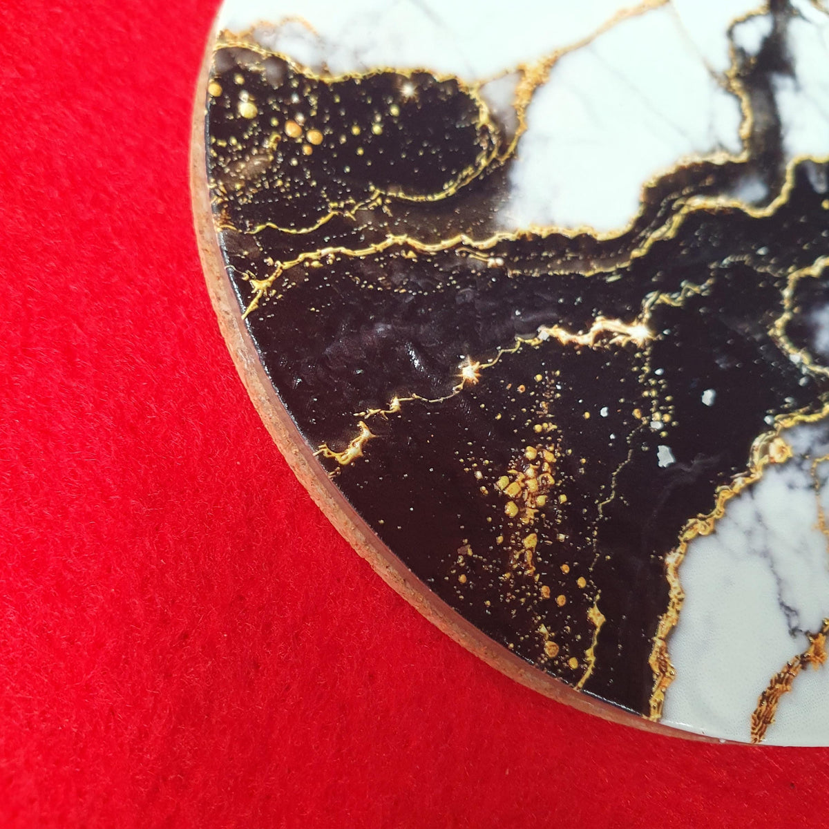 Luxury black marble effect coaster with white marble sections and elegant gold veining.