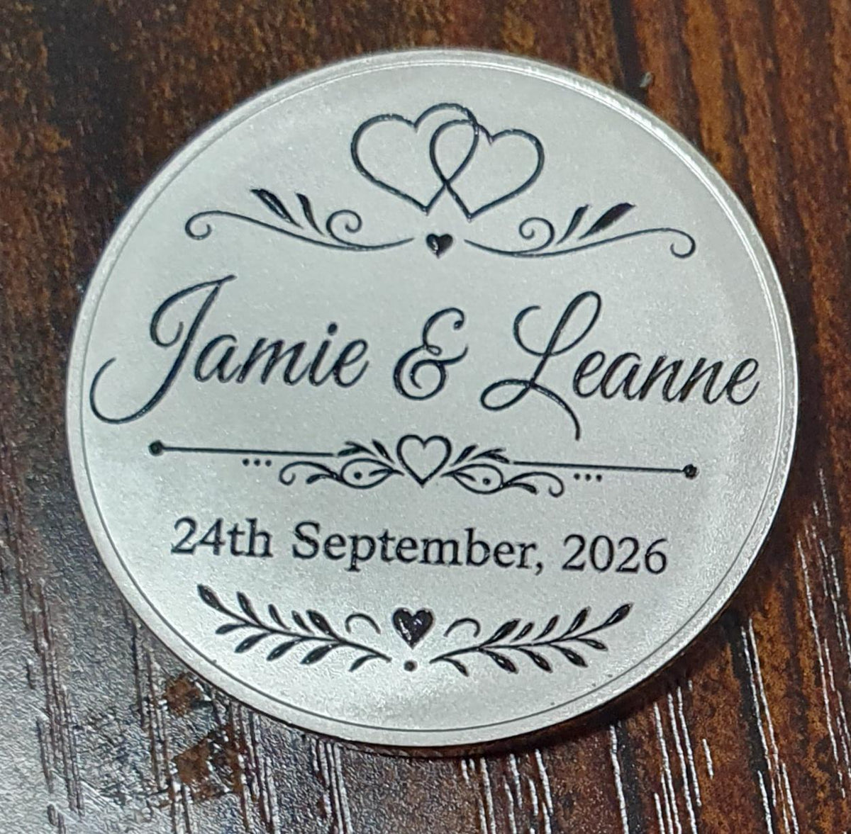 Personalised silver wedding keepsake coin engraved with couple's names and wedding date.