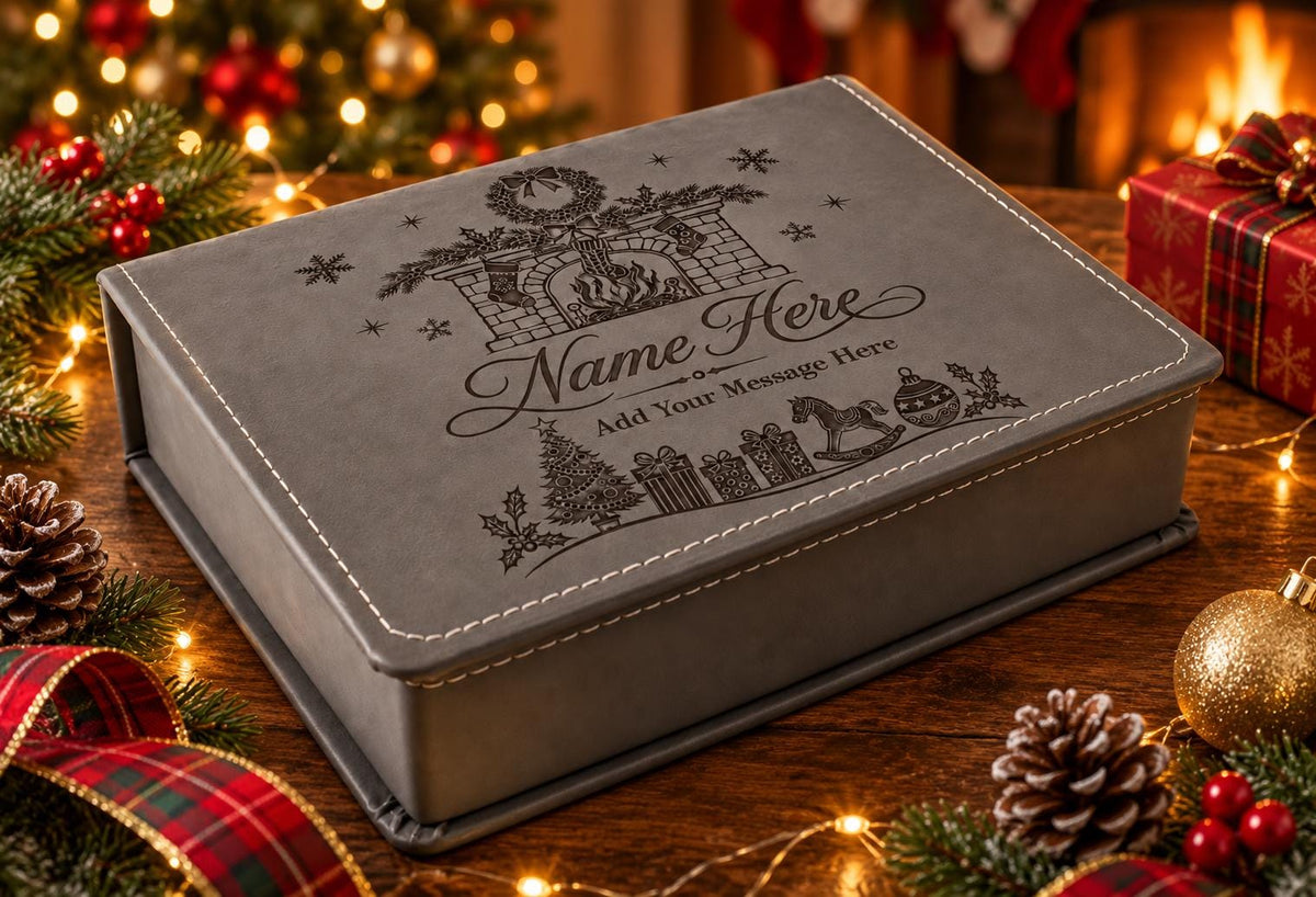 Grey personalised gift box with an engraved Christmas fireplace design on the lid, surrounded by lights, greenery and baubles.