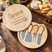 Round wooden cheese board with funny engraved charcuterie definition and four cheese tools stored neatly in the open base.