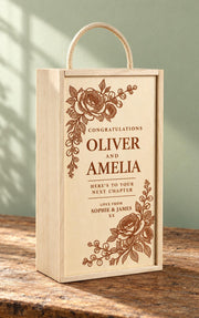 Personalised wooden double wine box with floral engraving, Oliver and Amelia’s names, a sliding lid and rope handle on a rustic table.