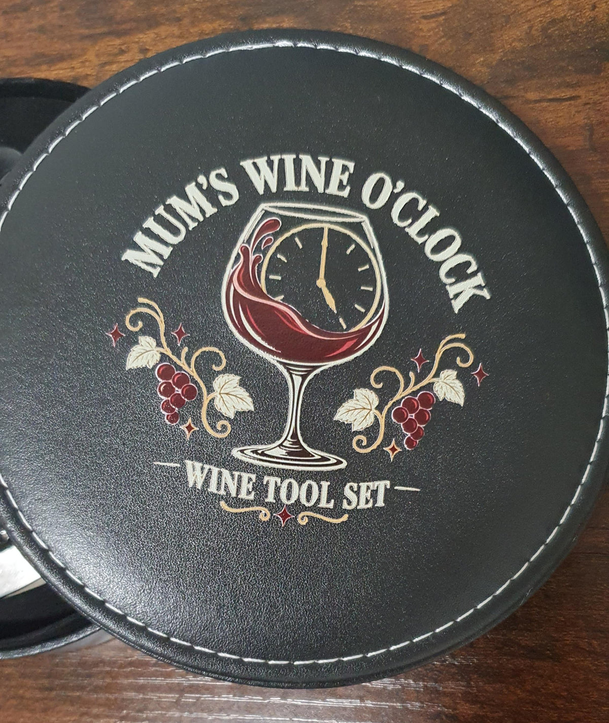 Close-up of the round black case lid with a wine glass clock illustration, grapes and “Mum’s Wine O’Clock” text.