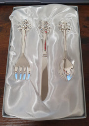 Silver plated teddy bear cutlery displayed together in an open gift box with soft white satin-style lining.