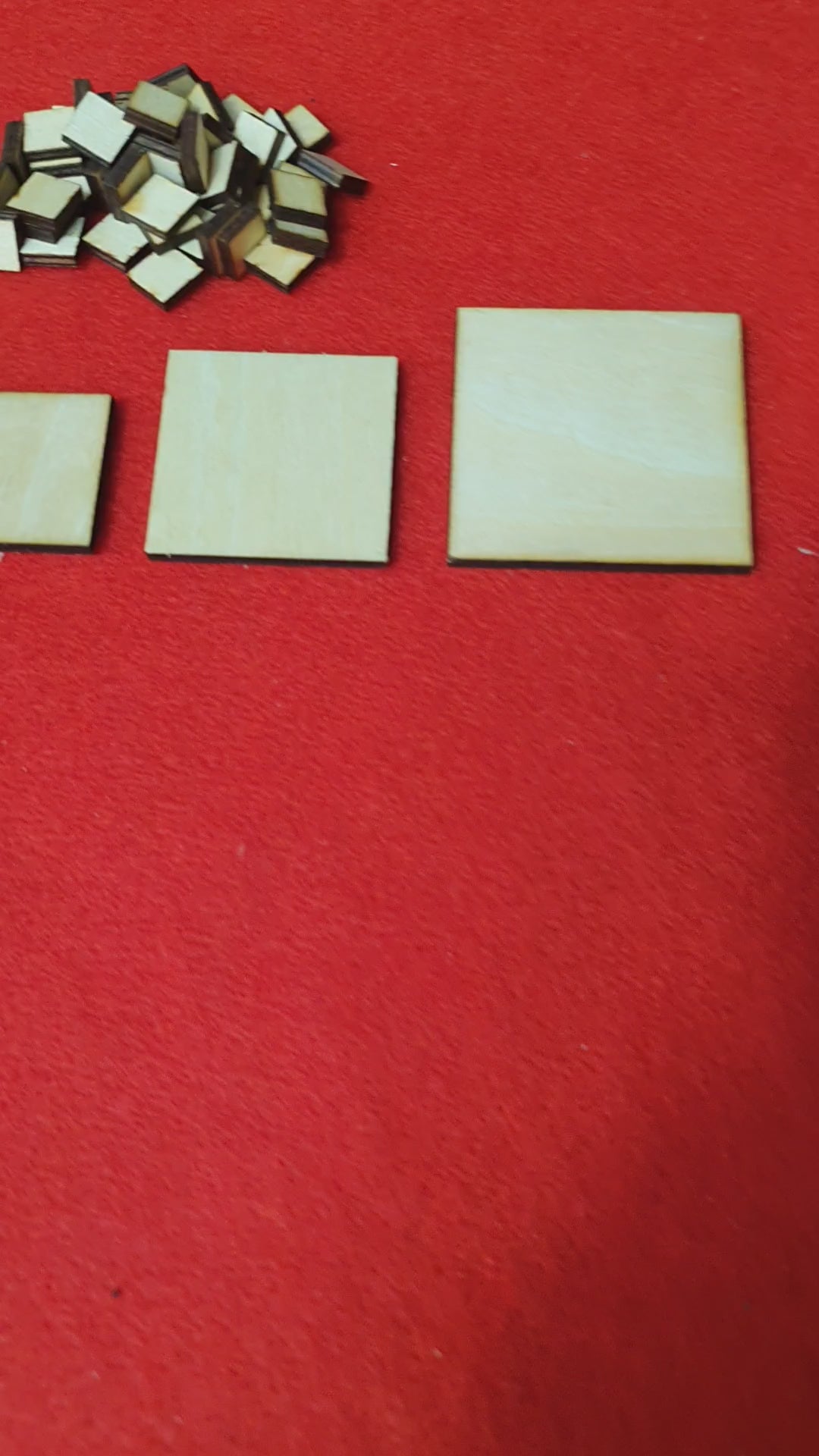 Load video: Close up of laser cut wooden square blanks showing natural woodgrain finish.