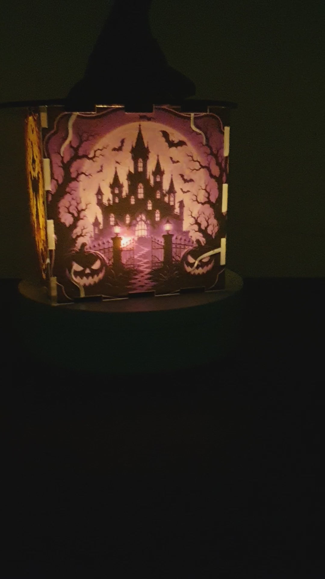 Load video: A Halloween-themed decorative box with a black witch hat on top and a spooky orange and black haunted-house illustration on the front, displayed on a white pedestal against a white wall.