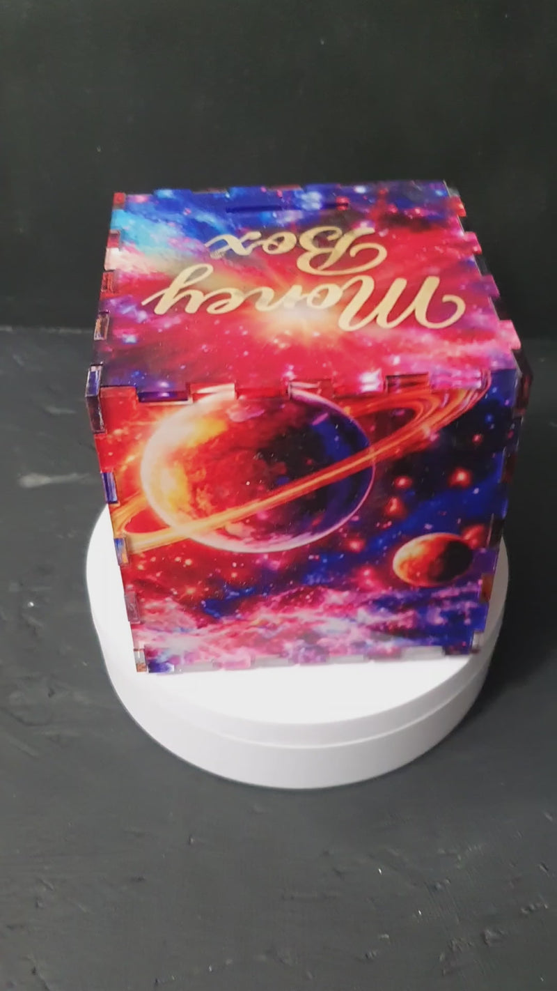 Front view of Stars and Planets money box with colourful galaxy design and “Money Box” text on lid, featuring vibrant red and blue nebula artwork.