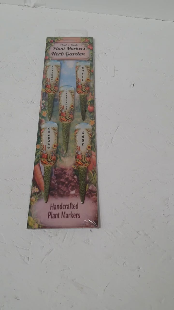 ALT Text 5:
Set of five 10cm herb plant labels arranged in packaging on grass surrounded by small colourful flowers, suitable for garden beds, pots and greenhouse use.